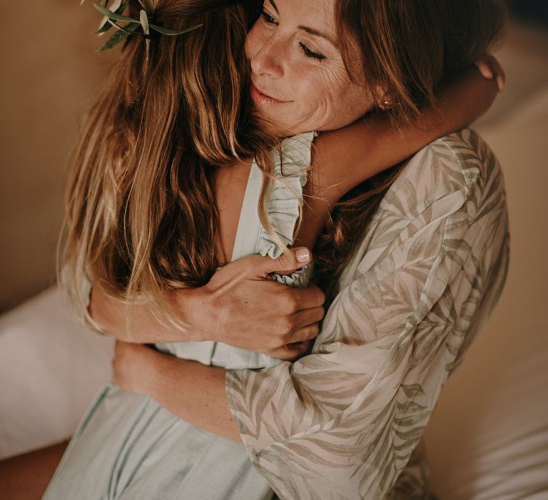 Bride getting ready with her daughter who wears olive leaves in her hair