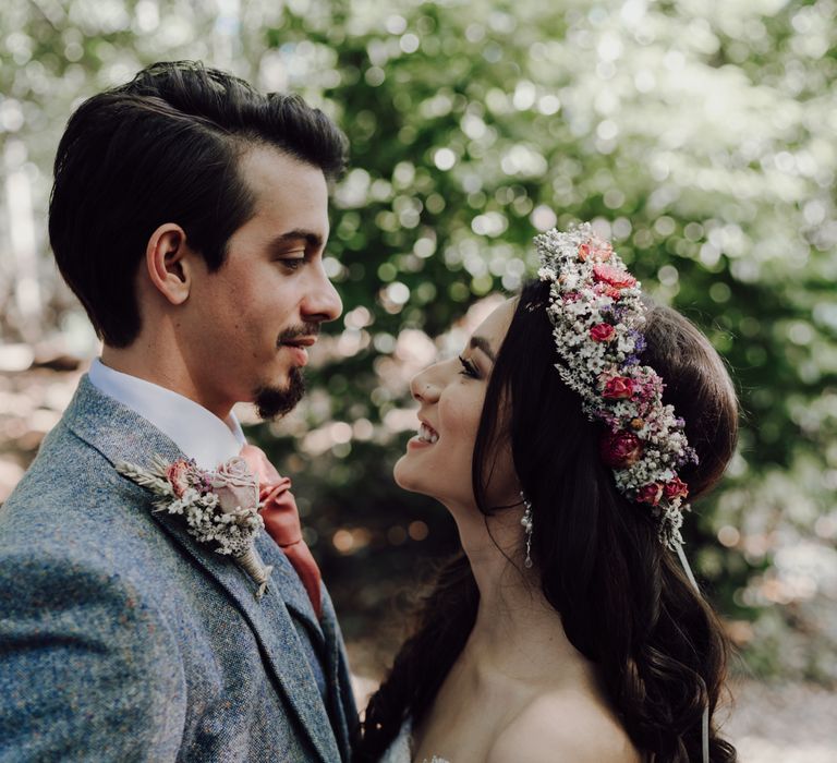 Bride and groom look at each other in close up portrait shot. Bride wears beautiful dried flower crown.