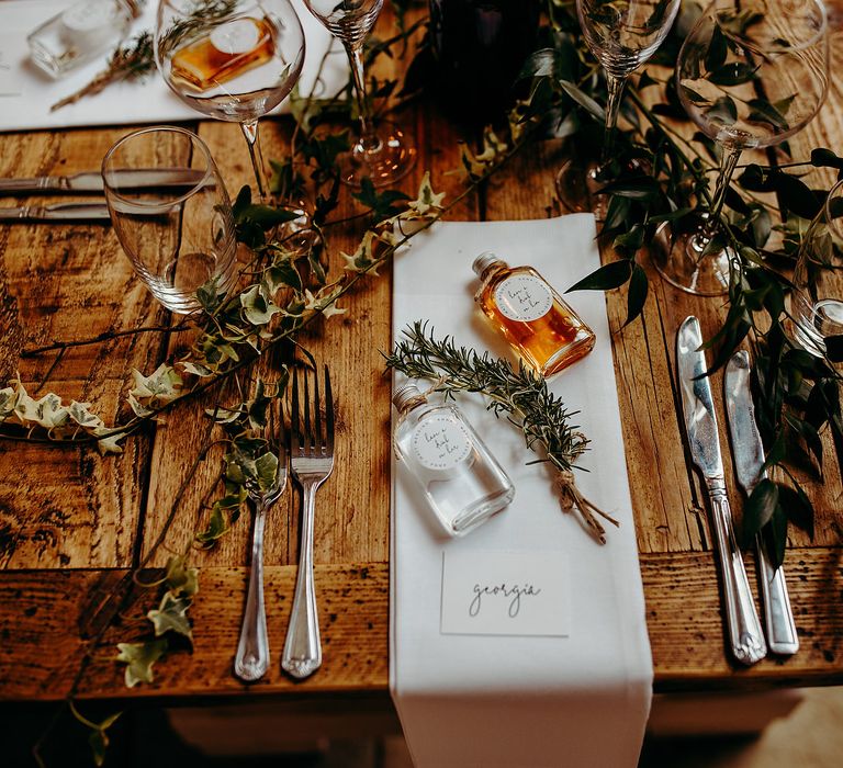 Rustic table decor with white wedding stationery and green foliage