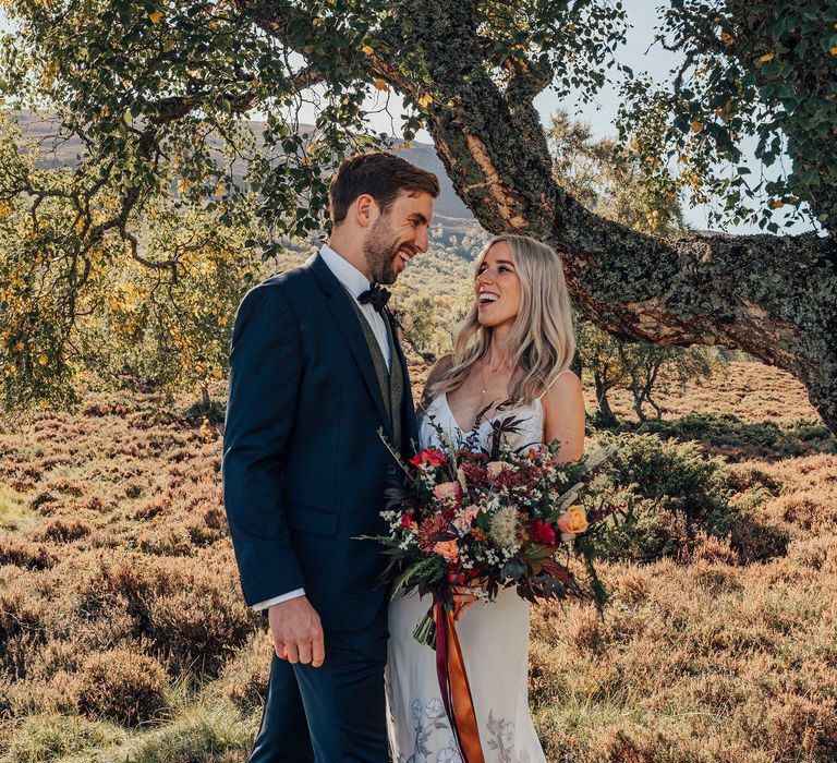 Bride & groom kiss in countryside at Woodland wedding