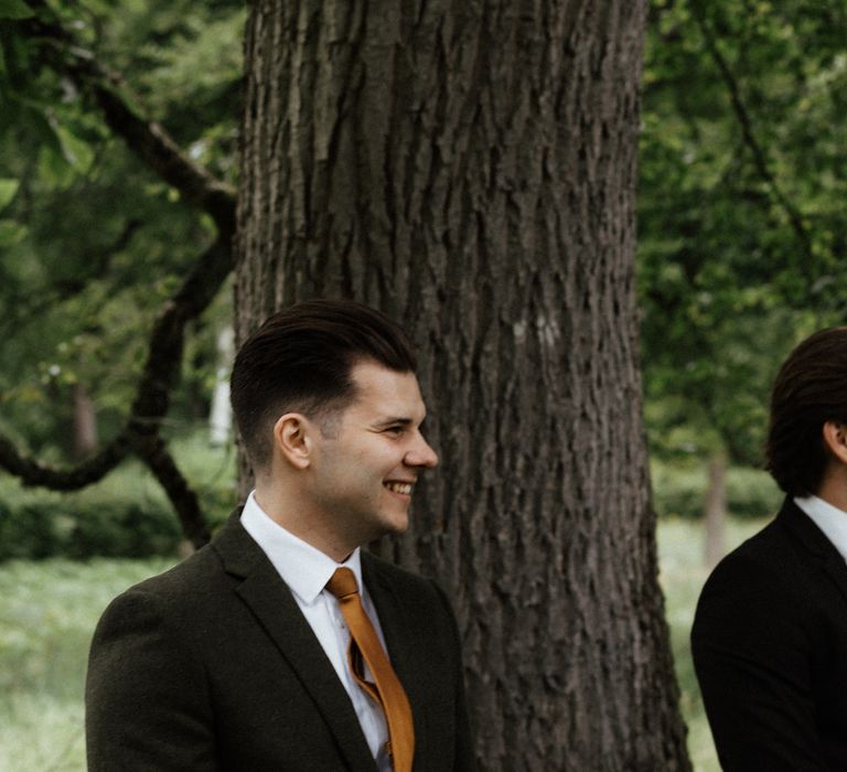 Groom waits for bride in woodland