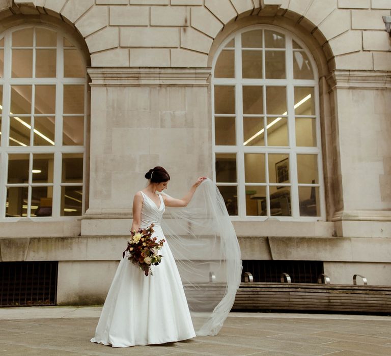 Bride holding her veil to one side outside Manchester town hall