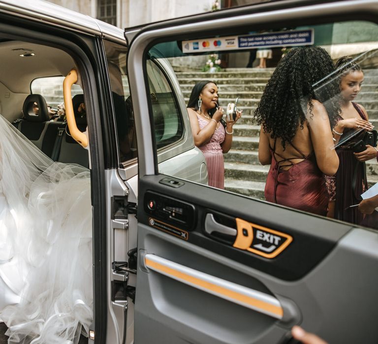 Bride in a princess wedding dress arriving at the St Anne's church in London in a black cab