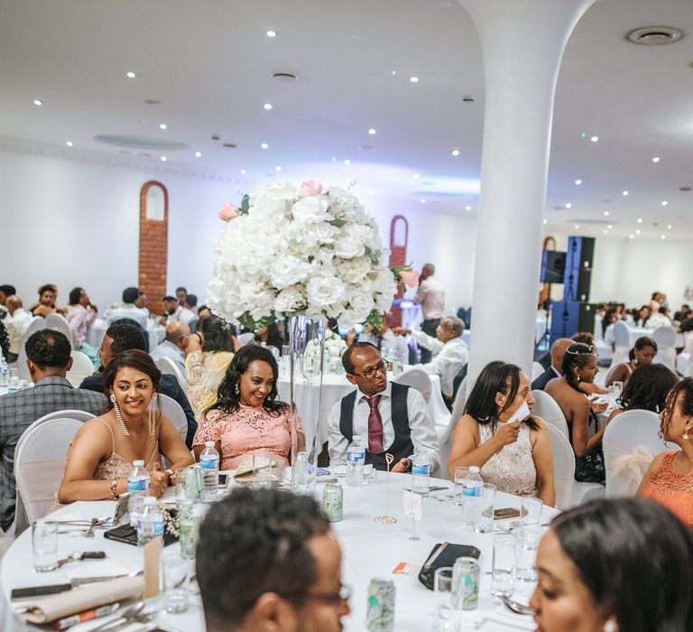 Tall all white floral centrepieces at Ethiopian wedding reception 