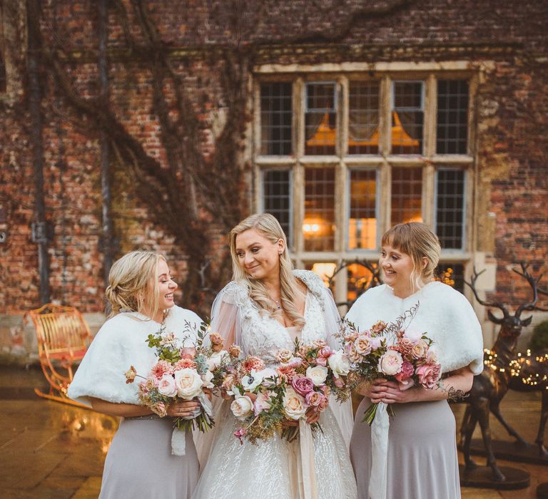 Bridal party portrait with bridesmaids in grey dress and white faux fur stoles holding blush pink and white wedding bouquets at Goldsborough Hall wedding