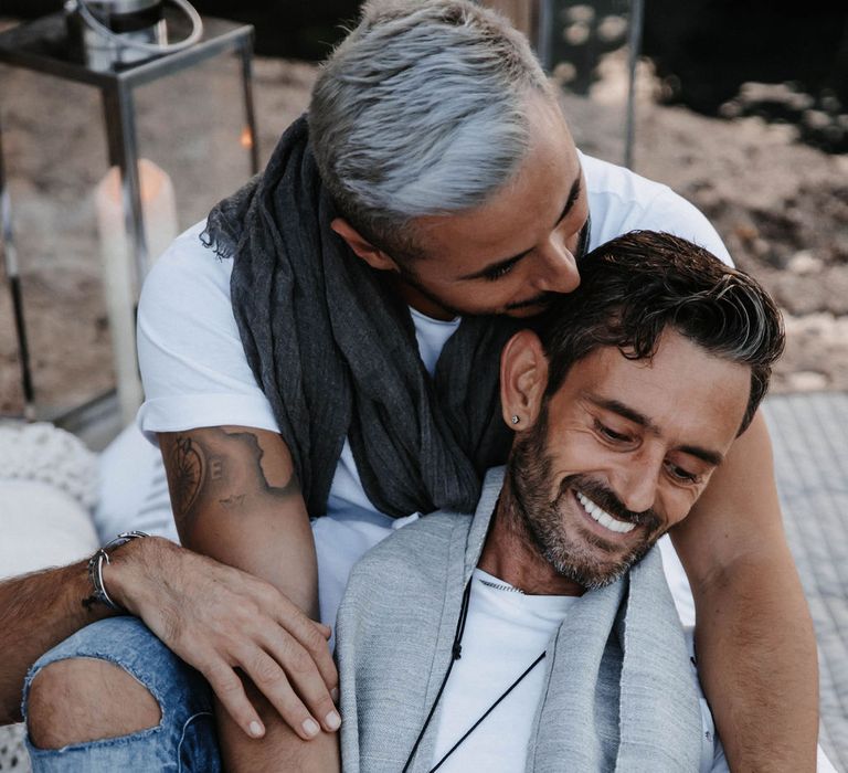 Grooms laugh together and embrace during engagement session