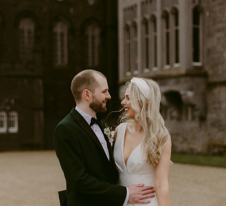 Blonde bride looks at groom whilst stood outside of Markree Castle 