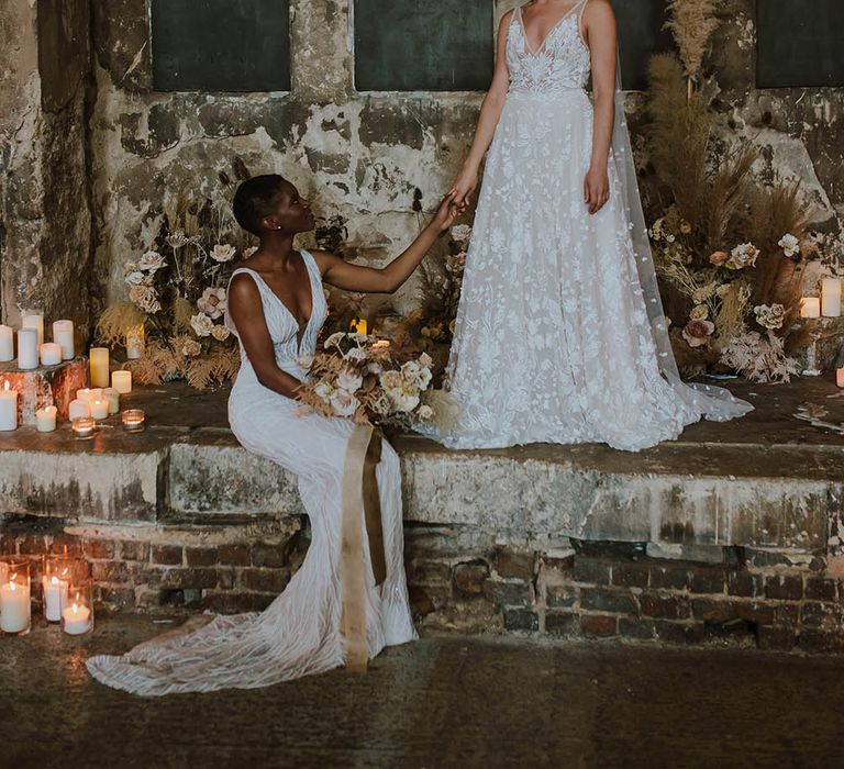 Bride in an appliqué wedding dress and veil standing at The Asylum altar with her bride sitting down in an embellished wedding dress