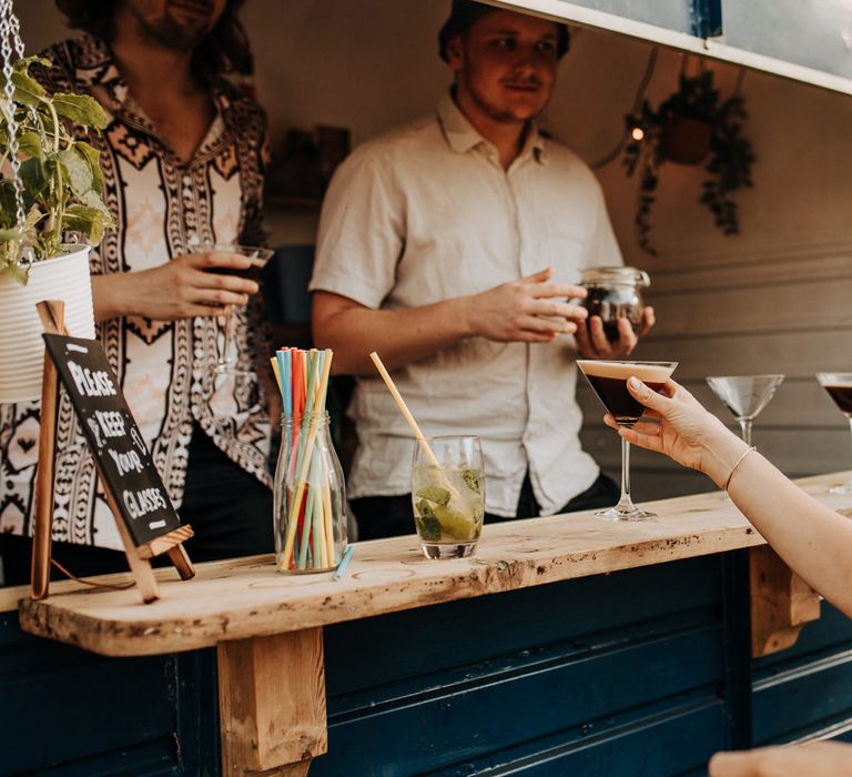 Guest picks up espresso martini from horse box bar at garden wedding reception