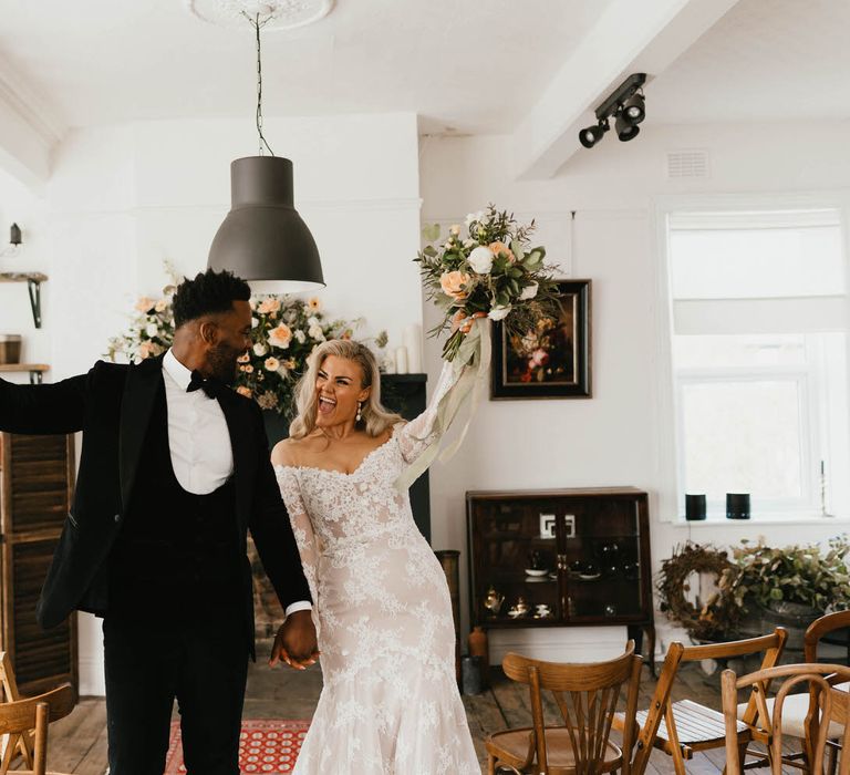 Bride and groom dancing back up the aisle with their hands in the air