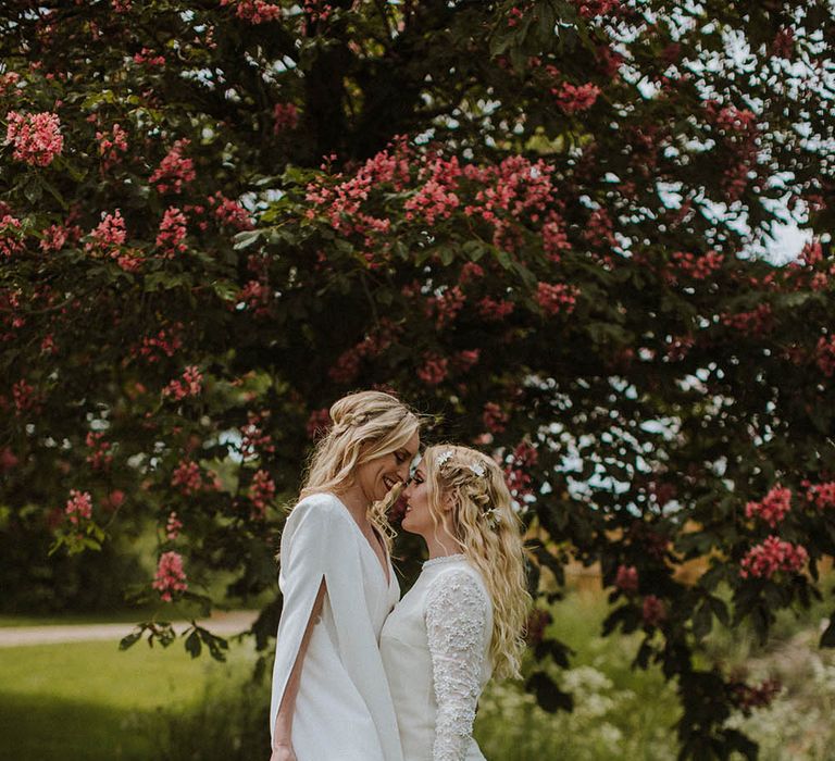 Intimate portrait of two brides holding a white peony and giant daisy bouquet with flowers in their hair 