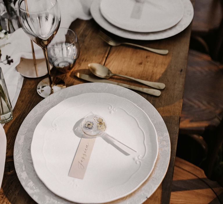 Place setting with ornate table ware and edible flower lollipop favour