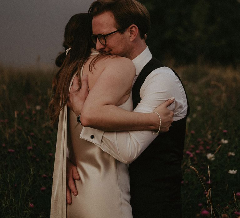 Bride & groom hug outdoors on the day of their wedding within the countryside