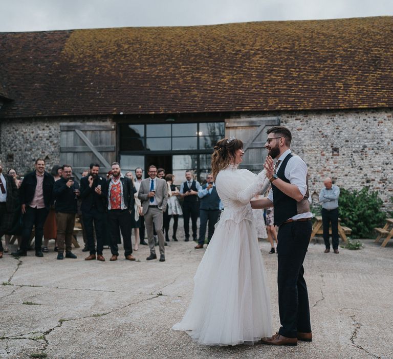 Bride & groom stand outdoors for first dance on their wedding day in rustic farm setting