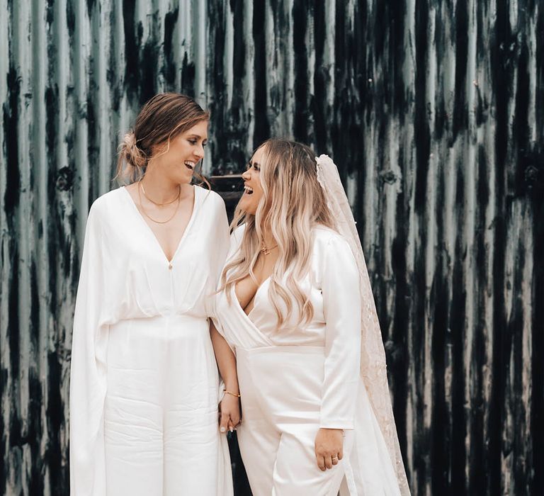 Brides look lovingly at one another as they stand together for couples portraits 