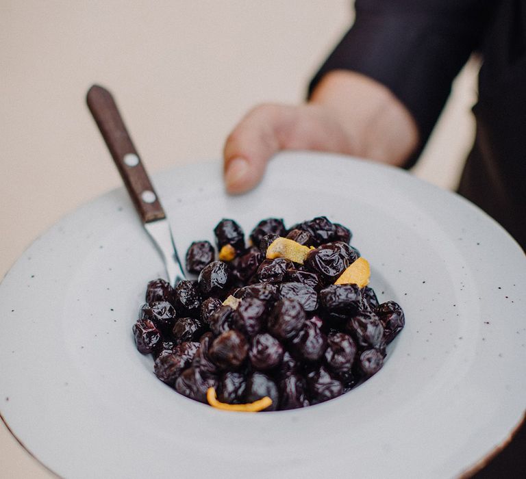 Black olives with orange peel in white plate