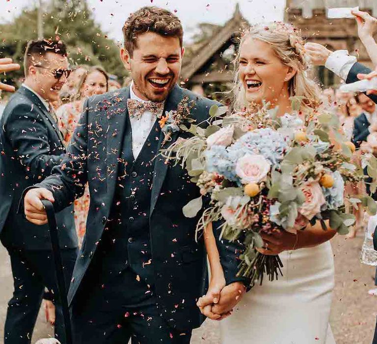 Confetti moment for bride and groom with pastel bouquet