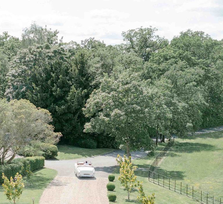 Bride and groom driving a vintage 1951 British Bentley Franay wedding car along the driveway at Botley's Mansion, Surrey