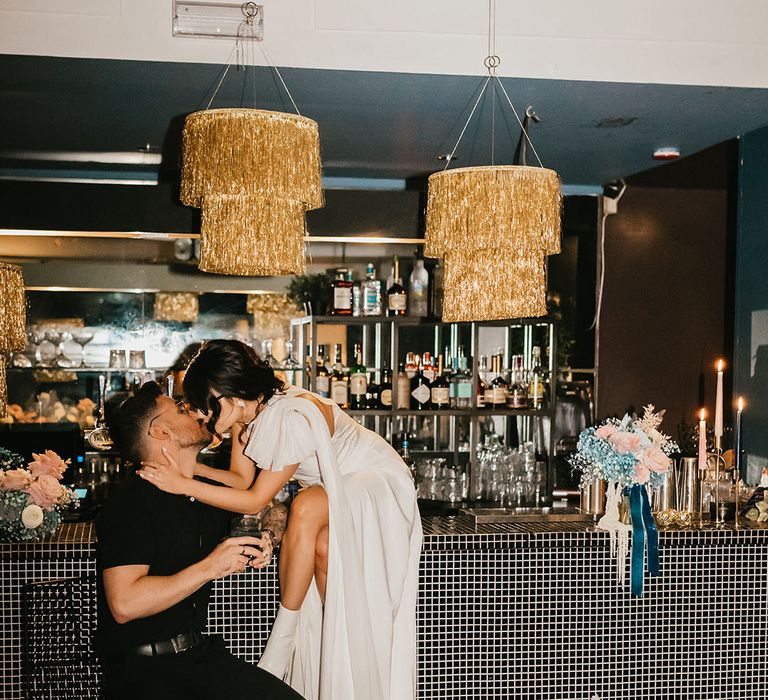 Bride kissing her grommet the stylish bar wedding wedding reception with gold glitter balls 