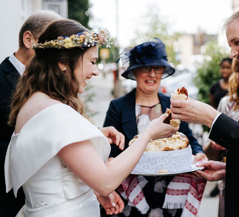 Bride & groom stand outdoors with cake on their wedding day