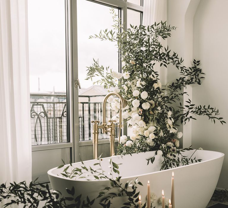 Roll top bath decorated with white flowers and green foliage at stylish Paris elopement wedding 