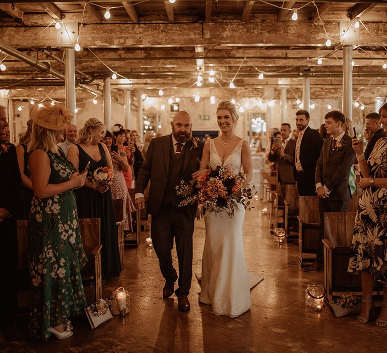 Bride walks down the aisle with her father on the day of her wedding