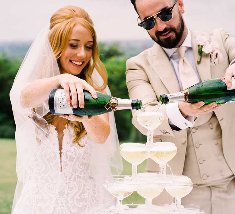 Bride & groom pour champagne into champagne glasses 