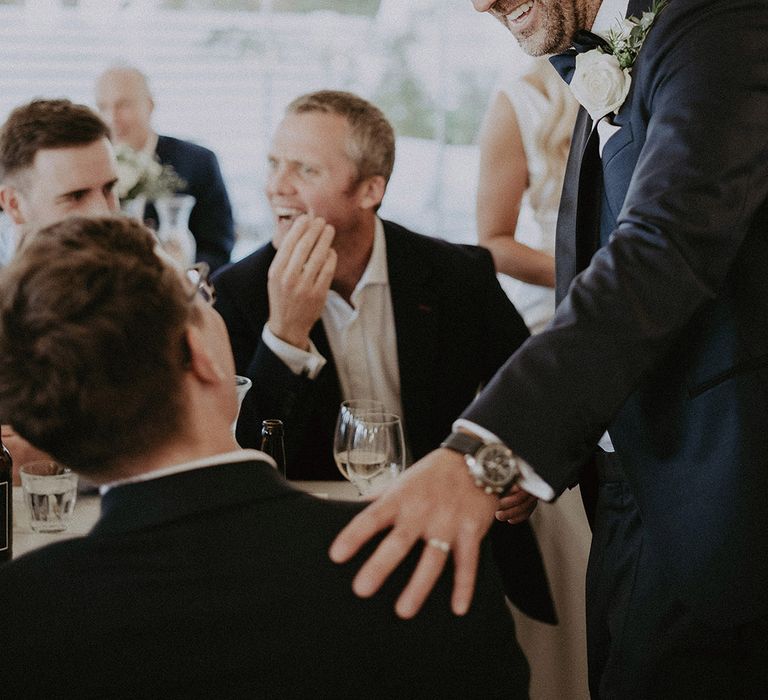 Groom chats to wedding guests at coastal venue