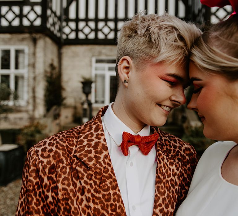 Bride with short blonde hair wearing a leopard print suit, red bowtie and eyeshadow 