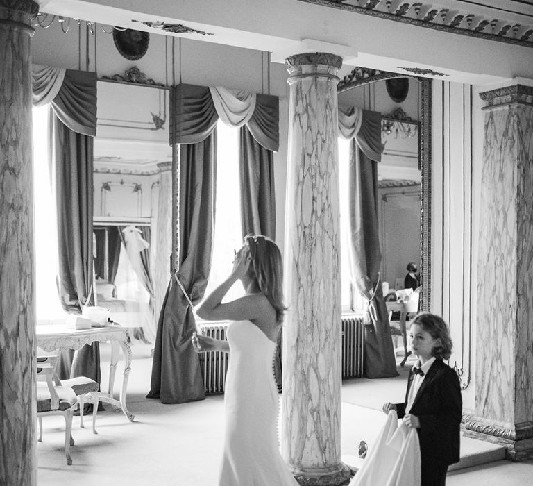 Son holds train of bridal gown during wedding day