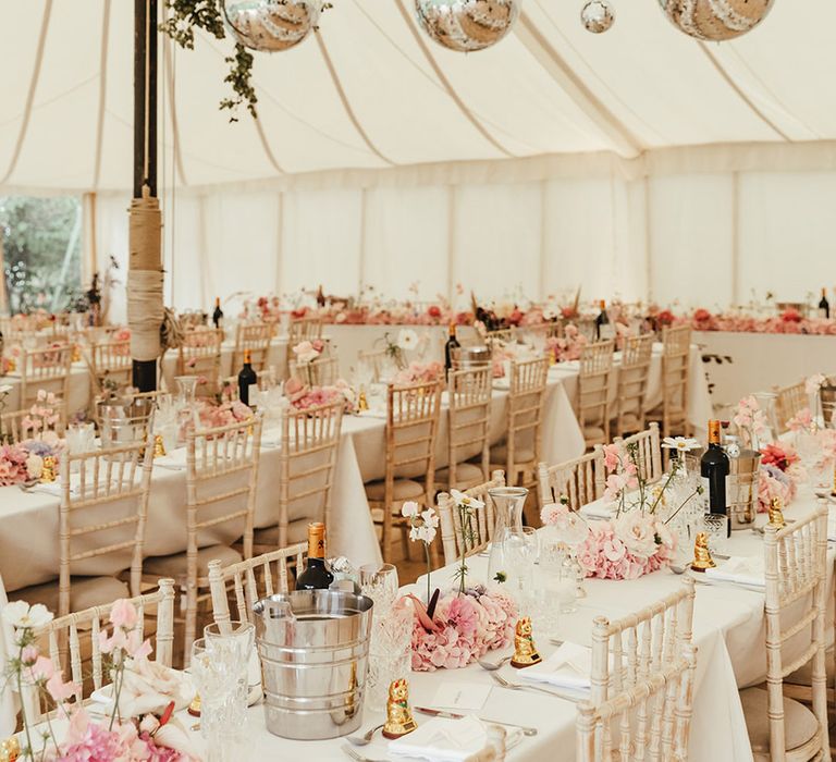 Marquee wedding reception with greenery and disco balls as well as a pink colour palette with small flower arrangements