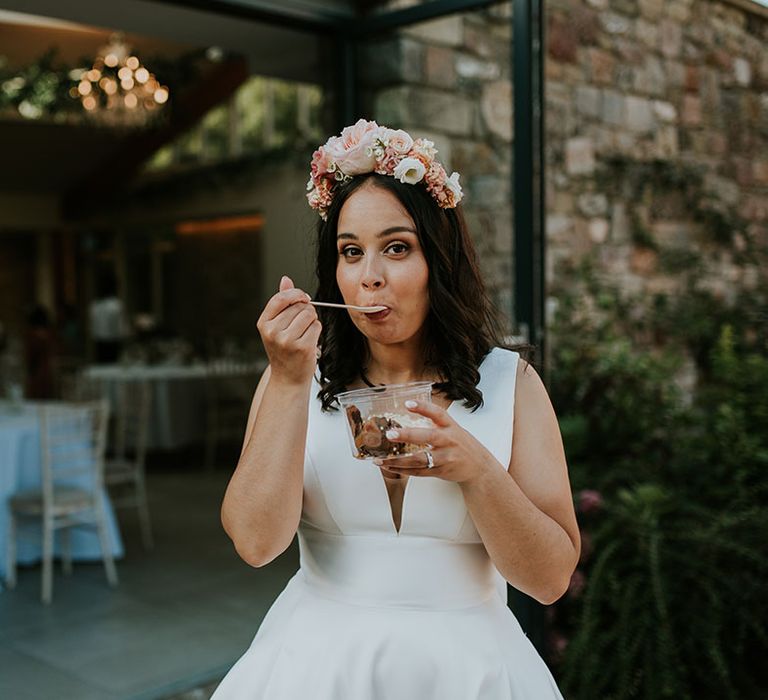 Bride helps herself to a pot of ice cream wearing pink flower crown and v-neck Stella York wedding dress