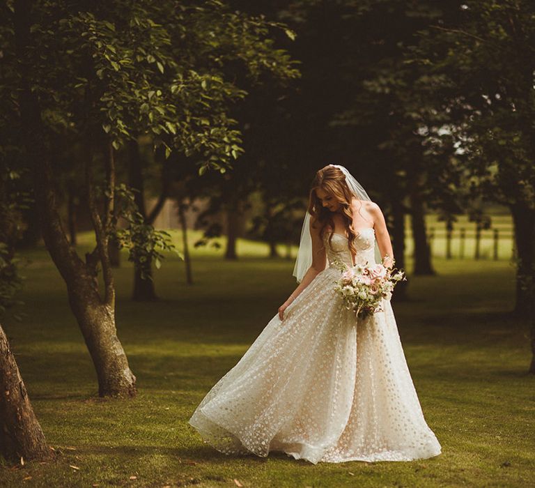 Bride looks stunning in sparkly Pronovias strapless wedding dress with flower detail carrying white and pink bouquet