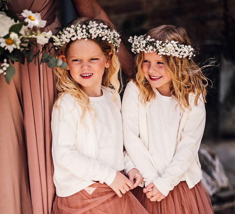 Flower girls with white flower crowns and pink tulle skirts with white cardigans 