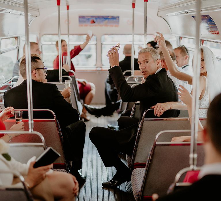 Wedding guests celebrate as they sit on their bus wedding transport 