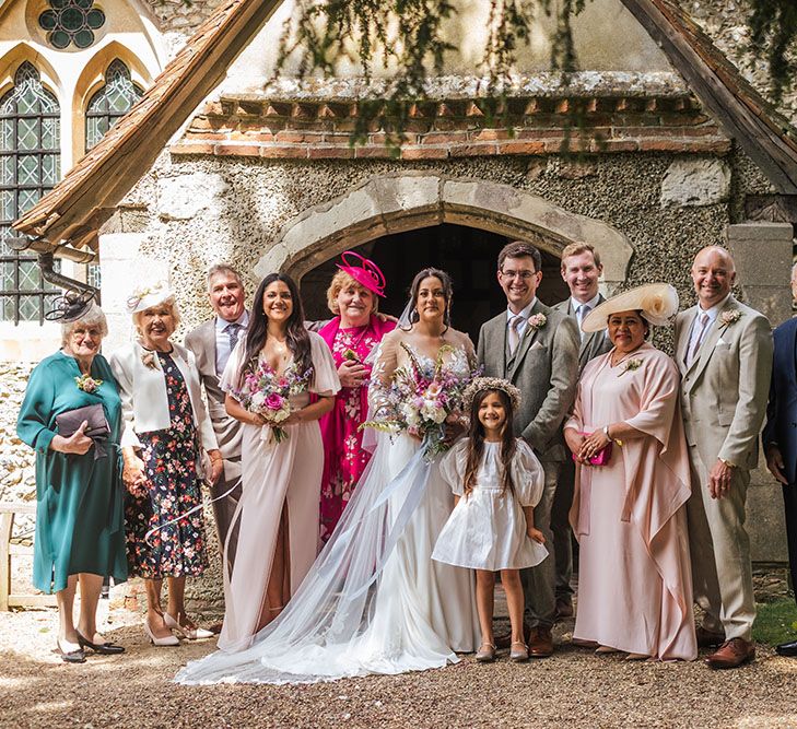 Bride & groom stand with family members outside church on their wedding day