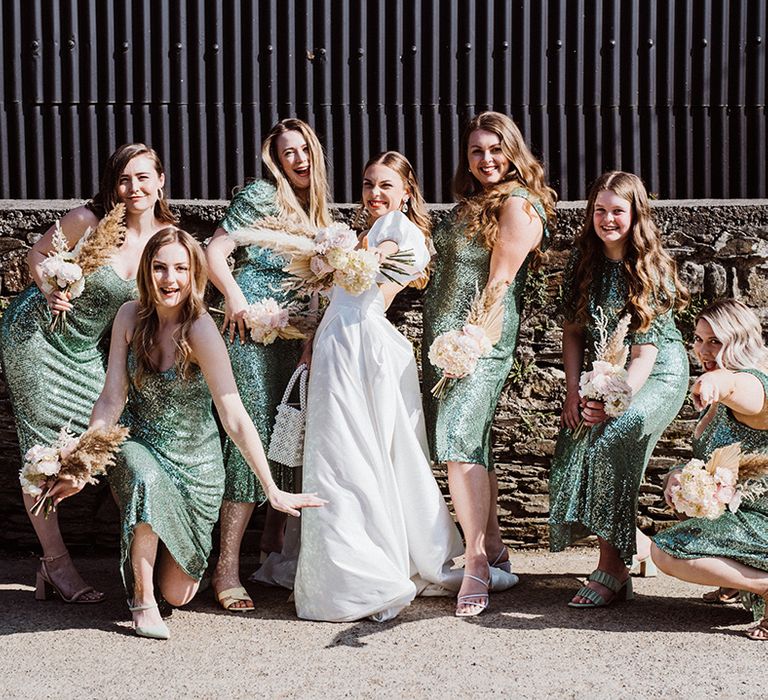 Bridal party shot with bridesmaids in sequin green dresses and bride in puff sleeve dress with dried flower bouquets 