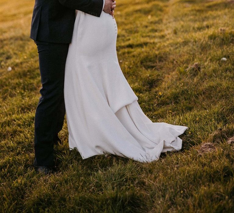 Golden hour wedding portrait with bride in a high neck Jesus Peiro wedding dress and groom in a blue suit