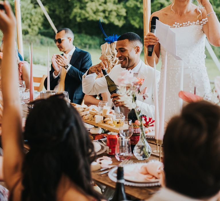 Bride stands up with a microphone reading out her bridal speech