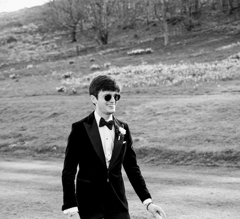 Groom wears black tie suit and plays croquet outdoors at Findon Place after wedding ceremony