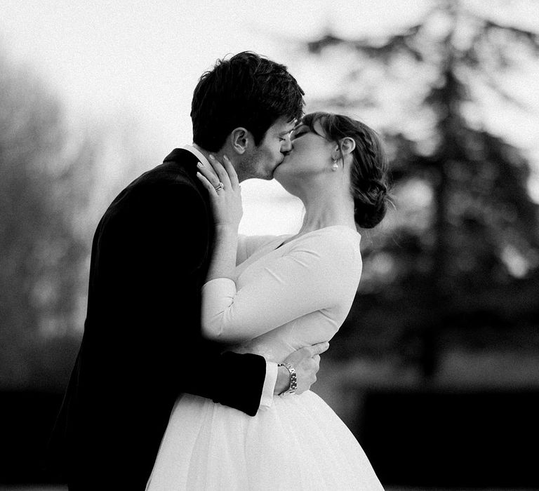 Groom kisses his bride who wears 1/4 length sleeve wedding dress with tulle princess skirt 