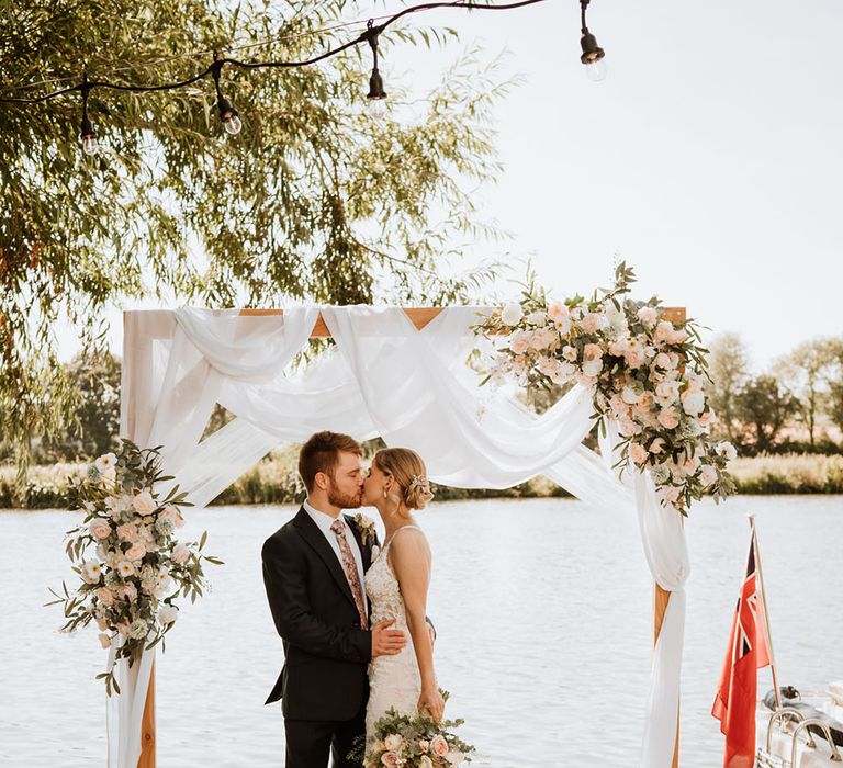 Bride & groom kiss in front of the Thames during outdoor humanist wedding ceremony 