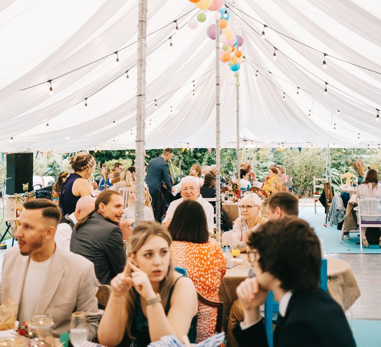 Colourful lanterns hang from secondhand marquee alongside festoon lighting 