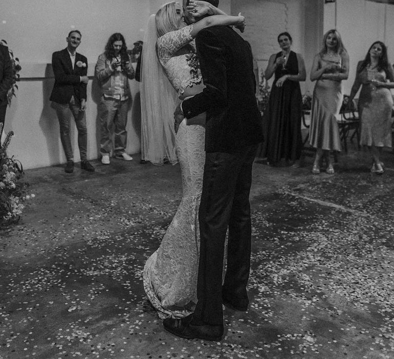 Bride in boho two piece lace bridal outfit and groom in dark tux with bowtie kissing at Hackney Studios wedding