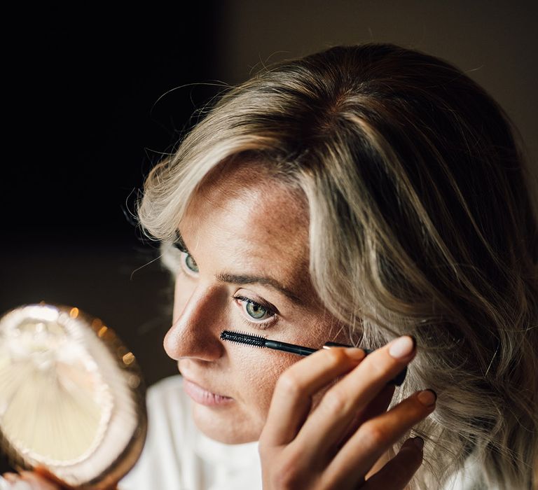 Bride puts on mascara and wears her short blonde hair in loose curls 