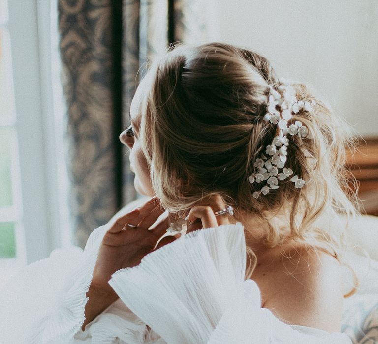 Bride in lace detailed wedding dress with long layered puff sleeves and roses hair clip with pearl details