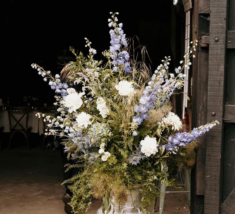 White and purple wedding flower arrangements in milk churns with foliage for rustic barn wedding 