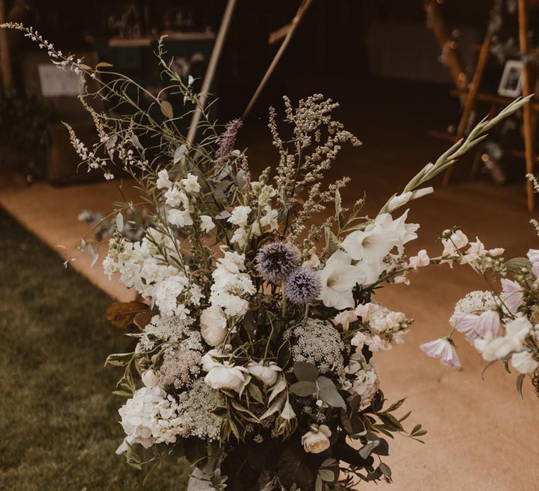 Traditional white and purple wedding flower arrangement in a milk churn for teepee wedding reception 