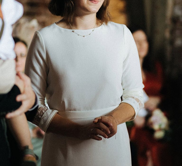 Bride in a simple traditional wedding dress with high neck in three quarter length sleeves with pearl and white headbands 