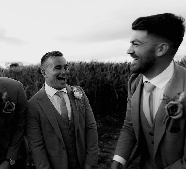 Groom laughs with his groomsmen in black & white image 